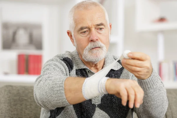 Hombre mayor está vendando su brazo —  Fotos de Stock