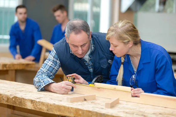 Tischlergeselle und Lehrling messen Holz — Stockfoto