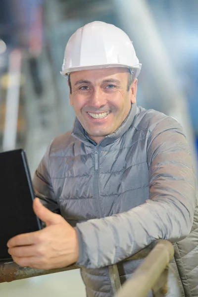 Hombre con casco trabajando con un ordenador portátil —  Fotos de Stock