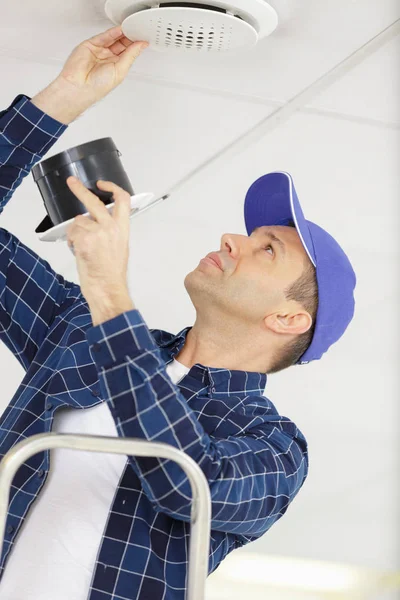 Jeune électricien installant un dispositif d'alarme incendie au plafond — Photo