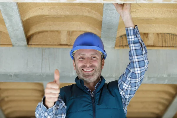 Smiling handyman wearing safety helmet and showing thumb up — Stock Photo, Image