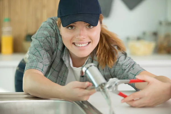 Kvinna rörmokare reparerar ett rör — Stockfoto