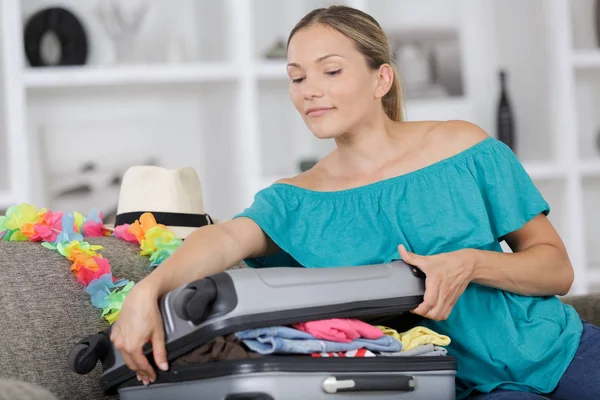 Счастливая молодая женщина собирает чемодан для поездки — стоковое фото