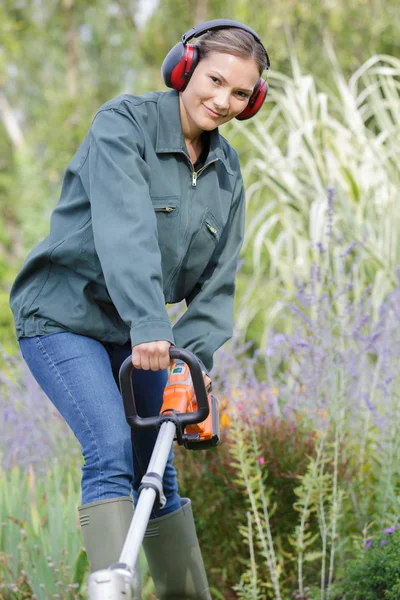 Mulher com cortador de grama na grama verde — Fotografia de Stock