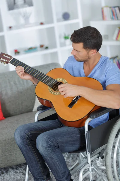 Άνθρωπος κάθεται σε αναπηρικό αμαξίδιο παίζοντας κιθάρα — Φωτογραφία Αρχείου