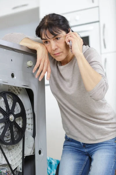 Mujer está llamando a un fontanero para reparar la fuga — Foto de Stock