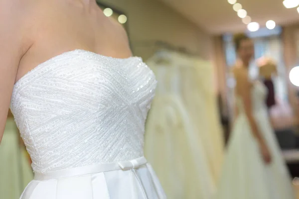 Kvinna försöker på bröllop klänning i brudsalong — Stockfoto