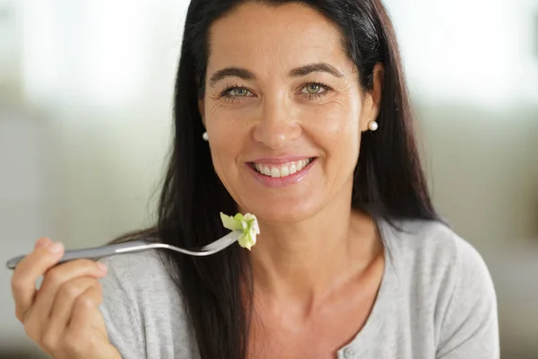 Mooie vrouw met salade op interieur achtergrond — Stockfoto