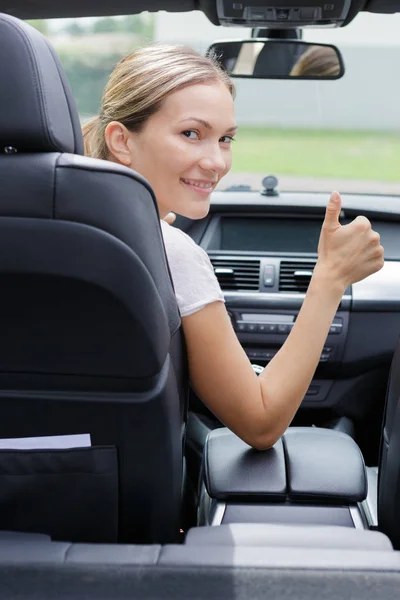 Female driver turning to back and making thumbs up gesture — Stock Photo, Image