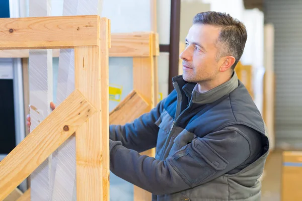 Trabajadores masculinos apilando materiales en marco de exhibición de madera — Foto de Stock