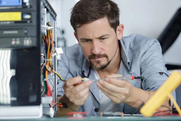 Koncentrovaný muž připojující kabel na desku s plošnými spoji — Stock fotografie