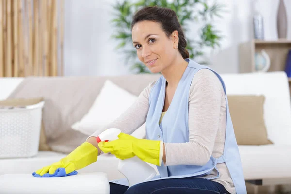 Mooie hard werkende vrouw spuiten reinigingsmiddel op het kussen — Stockfoto