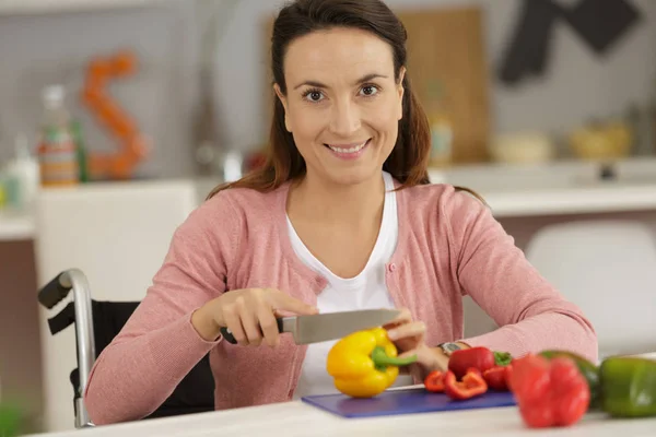 Mujer discapacitada en silla de ruedas preparando comida en la cocina —  Fotos de Stock