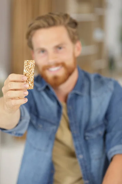 Young man holding a cereal bar — Stock Photo, Image