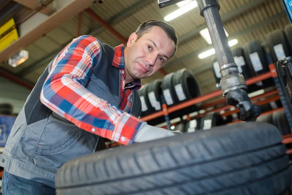 Homem verificando pneus em uma garagem — Fotografia de Stock