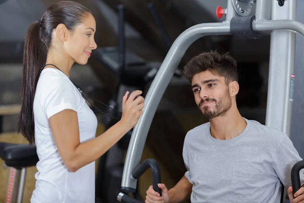 Jovem que trabalha com personal trainer no ginásio — Fotografia de Stock