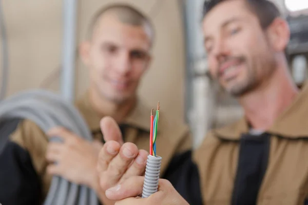 Builders looking at the cables coming out of grey trunking — Stock Photo, Image