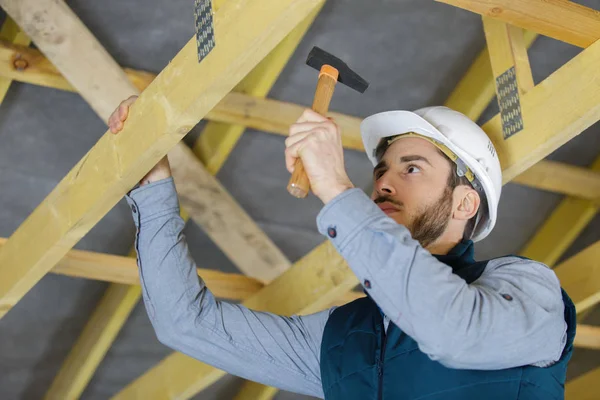 Säker byggnadsarbetare Hamra spik på planka — Stockfoto
