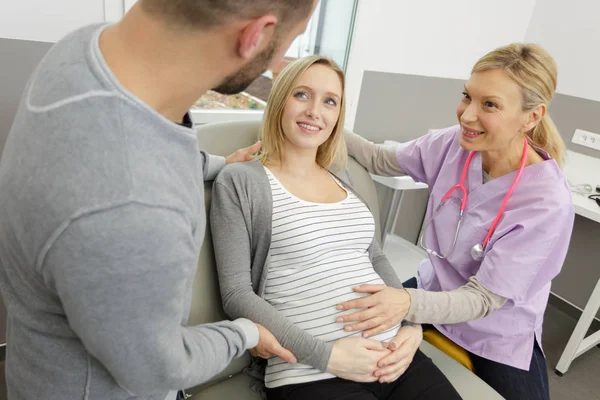 Felice donna incinta e marito in ospedale con il medico — Foto Stock