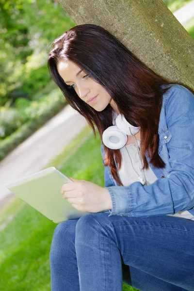 Junge Frau benutzt Tablet im Park — Stockfoto