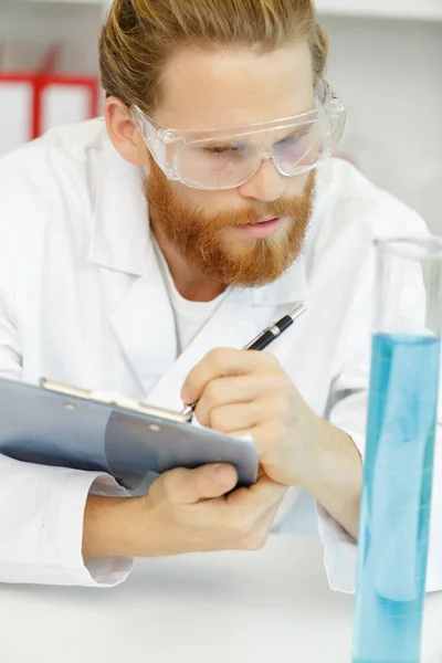 Retrato de jovem cientista fazendo anotações na cartilha — Fotografia de Stock