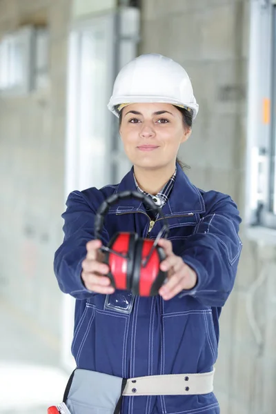 Mulher construtor segurando ruído cancelando fones de ouvido — Fotografia de Stock