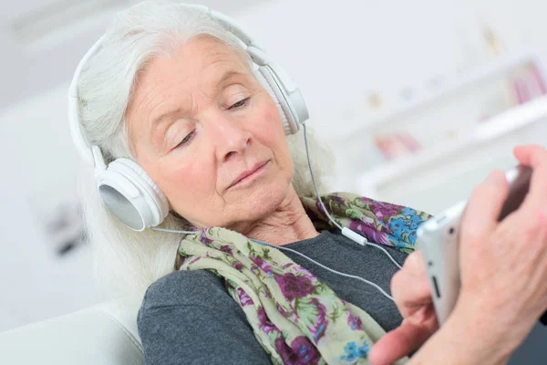 Starsza kobieta korzystających słuchania muzyki na tablecie PC — Zdjęcie stockowe
