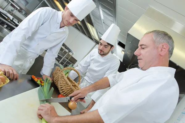 Restaurační pracovník a učni, stříhání čerstvých paprik salátu — Stock fotografie