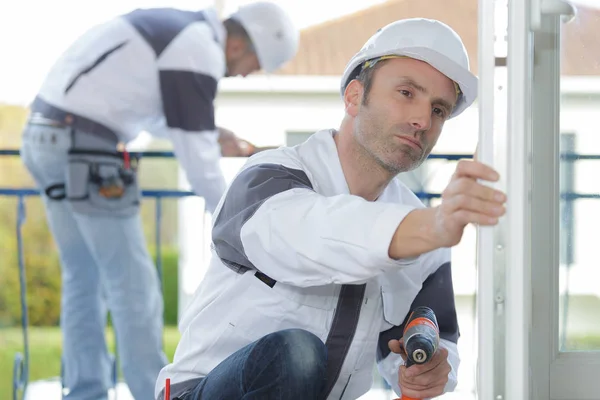 Male builder in the helmet looking at frame — Stock Photo, Image