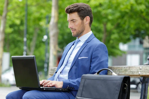 Serious businessman with laptop outdoor — Stock Photo, Image