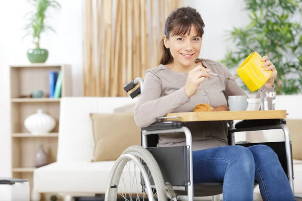 Pretty woman in wheel chair having breakfast — Stock Photo, Image