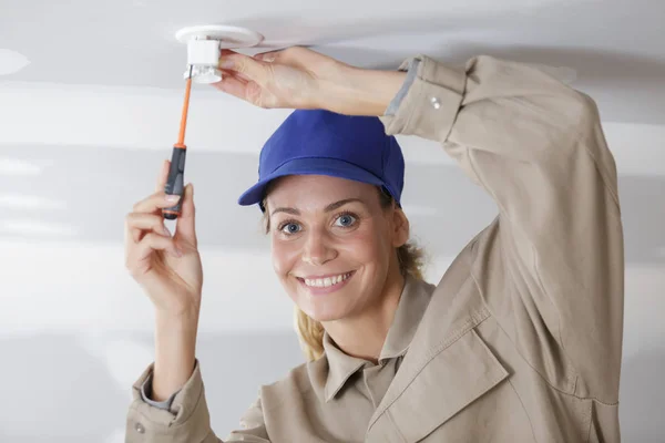 Mujer instalando una bombilla en el techo — Foto de Stock