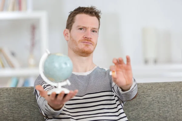 Homem segurando cartão SIM e globo no sofá — Fotografia de Stock