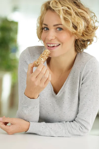 Mujer joven comiendo barra de cereal — Foto de Stock