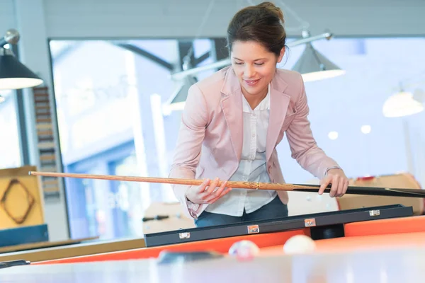 Smart woman holding cue by pool table — Stock Photo, Image