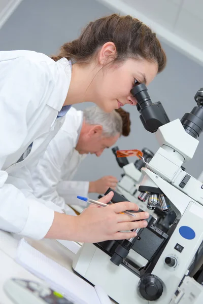 Cientista feminina olhando através de um microscópio em laboratório — Fotografia de Stock