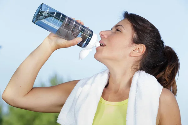 Pasuje, brązowe włosy do picia z jej butelkę wody — Zdjęcie stockowe