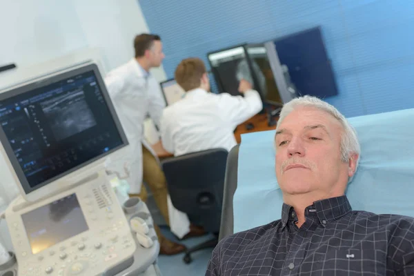 Homme posé sur le lit d'hôpital à côté de l'équipement de scanner — Photo
