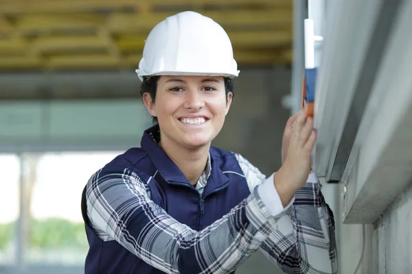 Lycklig kvinna håller byggare nivå — Stockfoto