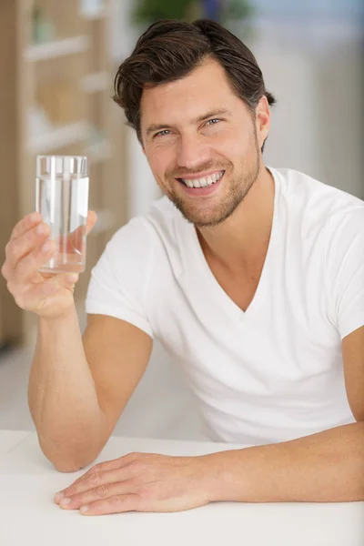 Счастливый человек, показывающий камере стакан воды — стоковое фото