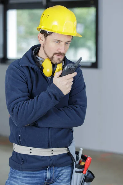 Jonge mannelijke bouwer communiceren door walkie talkie — Stockfoto