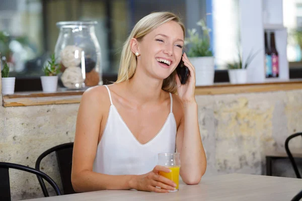 스마트 폰과 웃음을 사용하여 카페에서 아름다운 젊은 여성 — 스톡 사진