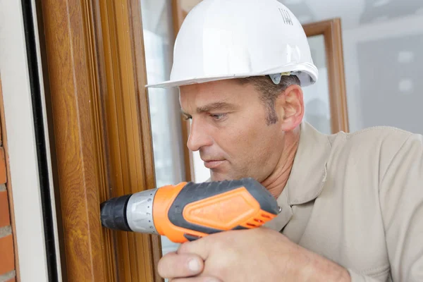 Mann bohrt Fensterrahmen an — Stockfoto