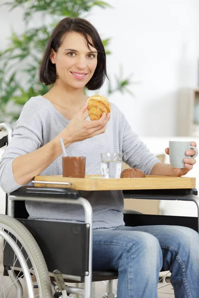 Mujer encantada en una silla de ruedas desayunando — Foto de Stock