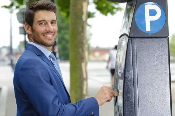 Portrait of businessman inserting coins into parking meter — Stockfoto