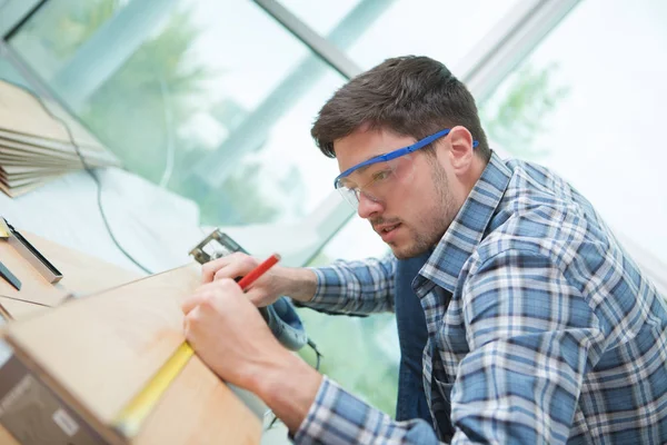 Hombre que mide tablones de madera con cinta y lápiz — Foto de Stock