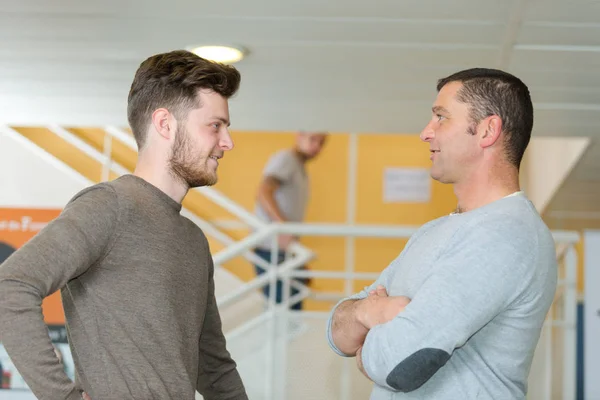 Positiva män som pratar i korridor — Stockfoto