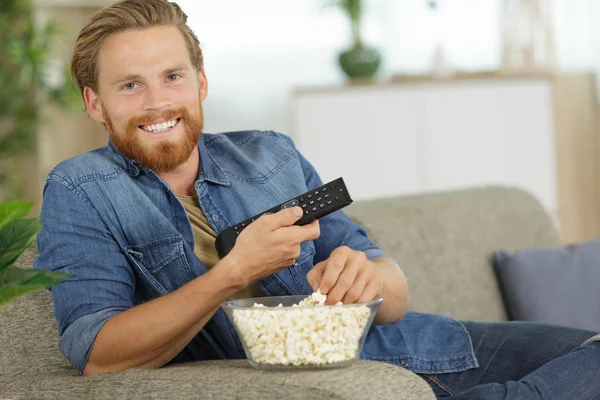 Homme souriant avec télécommande tv à la maison — Photo