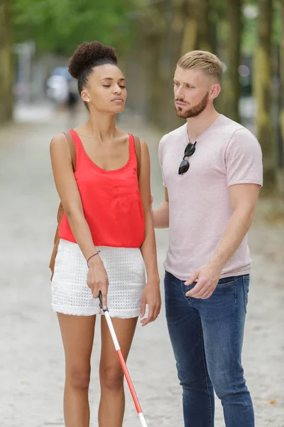 Uomo che assiste donna cieca con bastone bianco sulla strada — Foto Stock