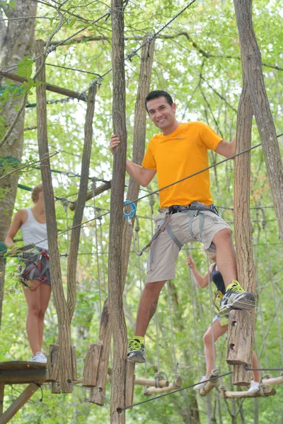 Casal em uma corda escalando no parque de aventura — Fotografia de Stock